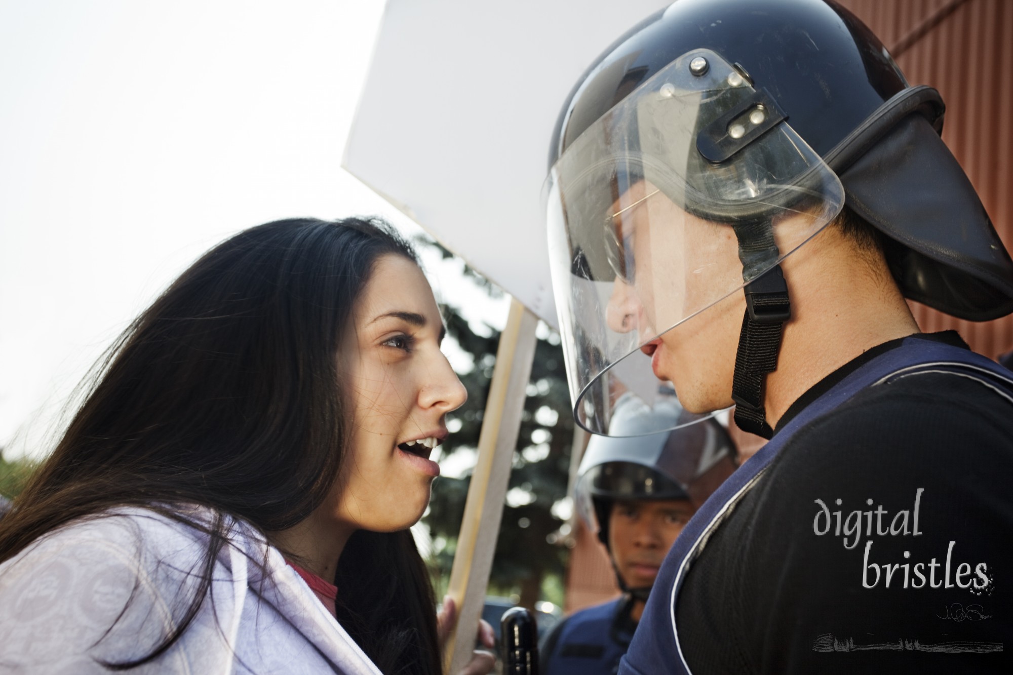 Student protester confronts riot gear clad police officer