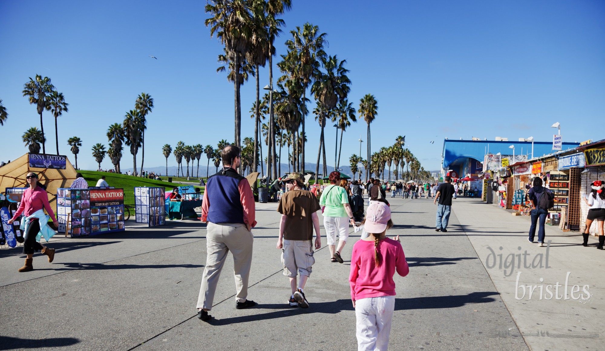 Ocean Front Walk in Venice Beach on a sunny Christmas Day. An eclectic mix of tourists, street performers, sidewalk vendors and homeless, the Boardwalk (as it is known) covers about one and a half miles. Facing north, looking towards Santa Monica, the park and Pacific Ocean are on the right