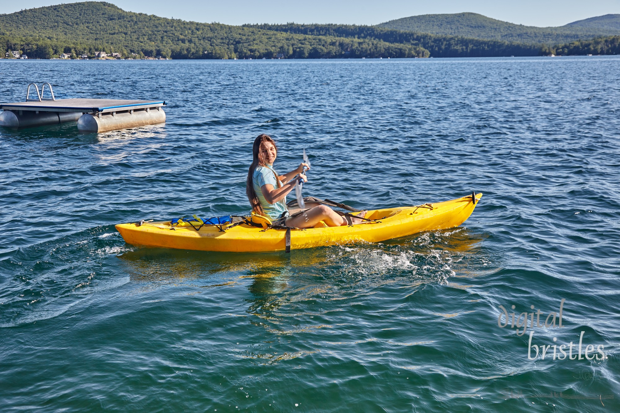 Teenage girl trying out a kayak on a sunny day at Merrymeeting Lake