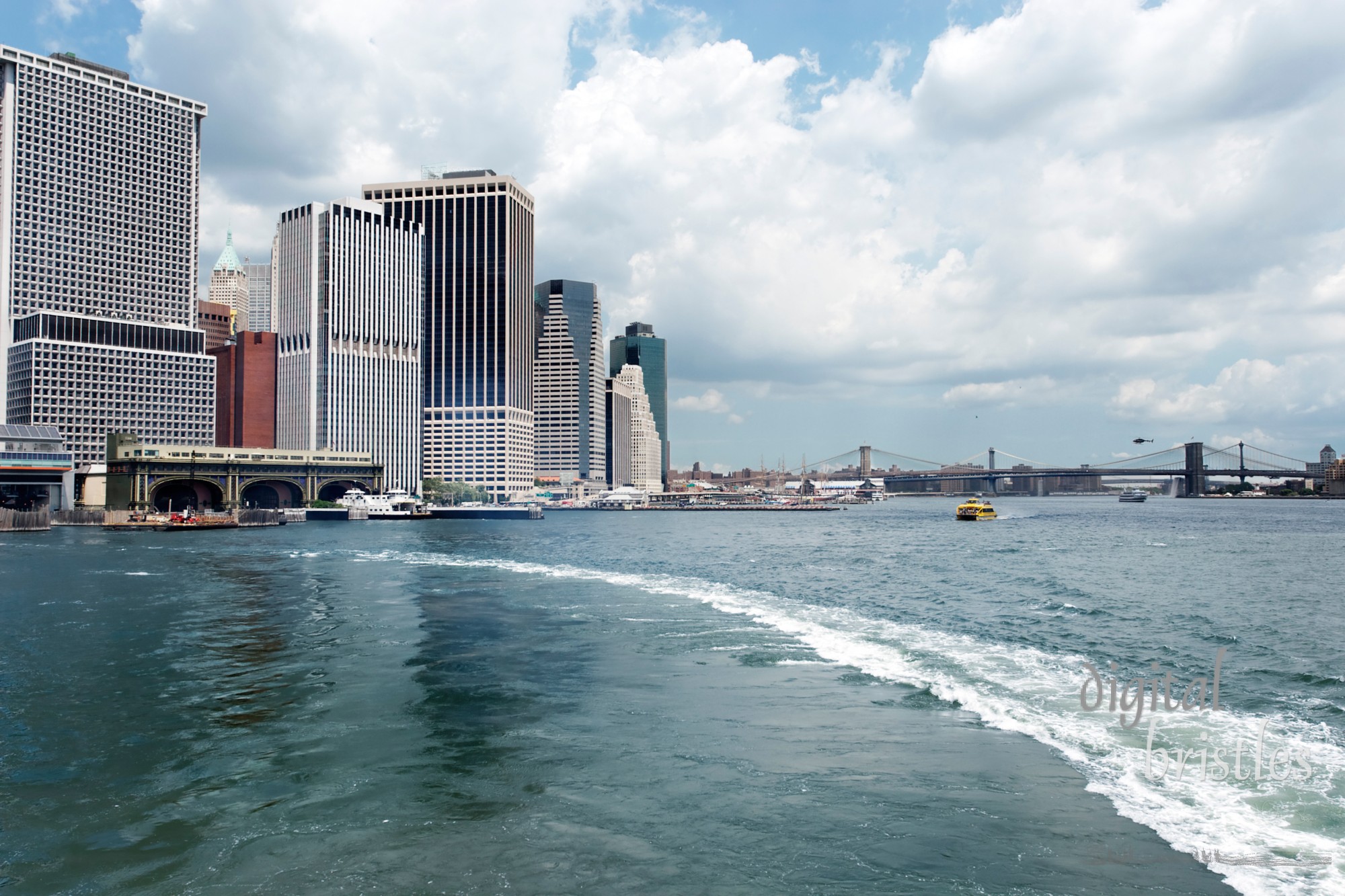 Staten Island Ferry's wake pulling away from the Governor's Island Ferry terminal with the Brooklyn Bridge and Lower Manhattan skyline