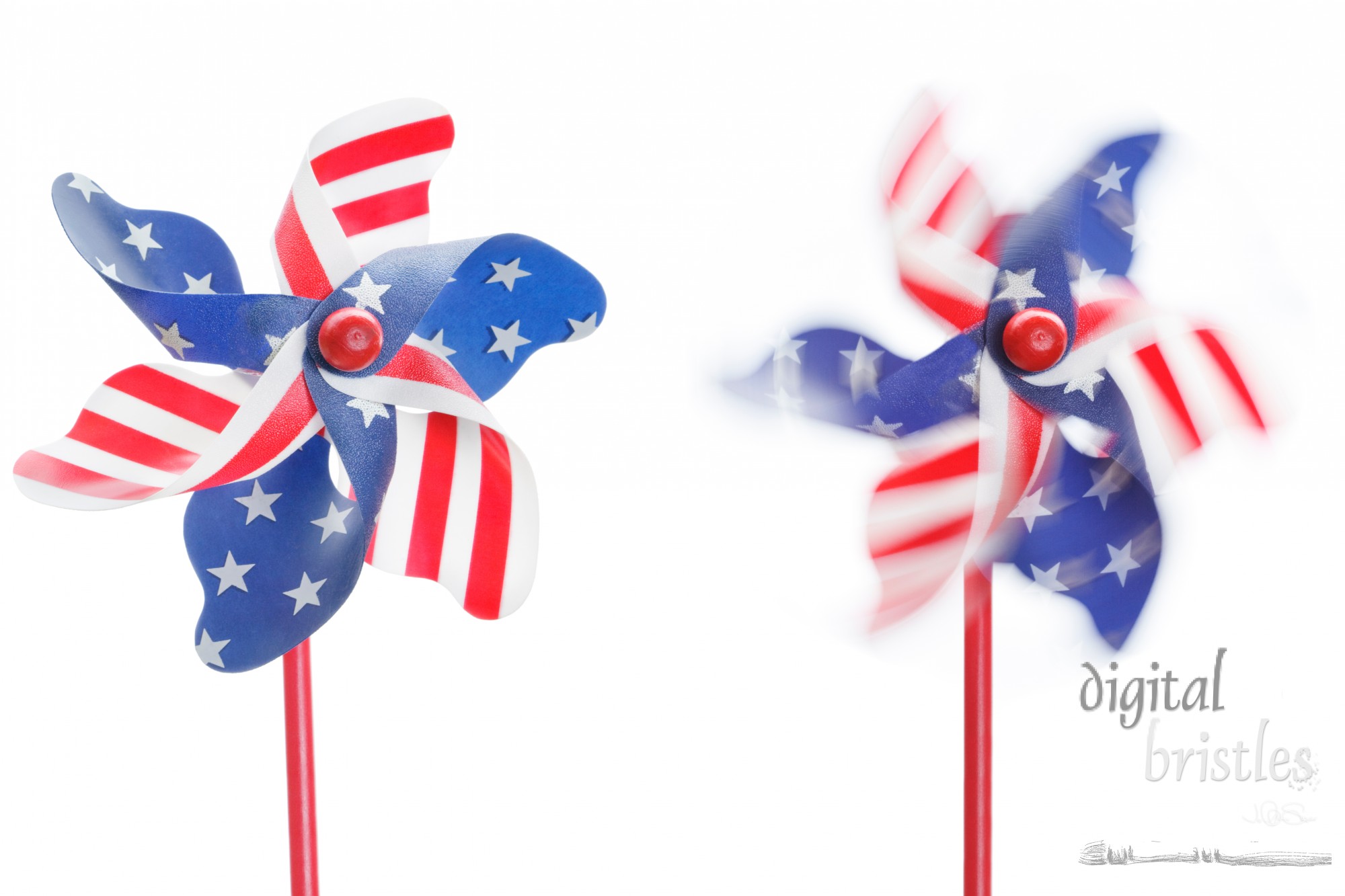 Two stars & stripes pinwheels, one stationary, one spinning, isolated