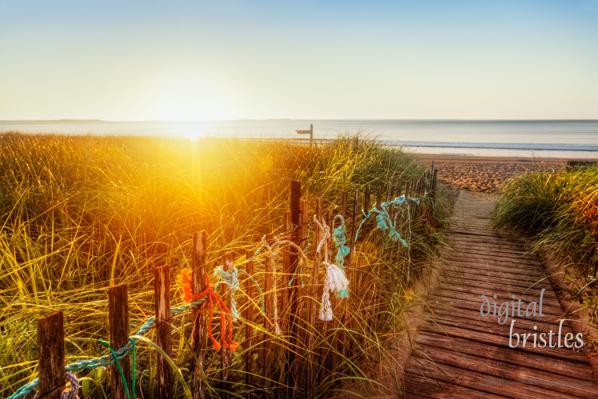 Sun at the horizon lights duenes and old-fashioned boardwalk on a Maine beach