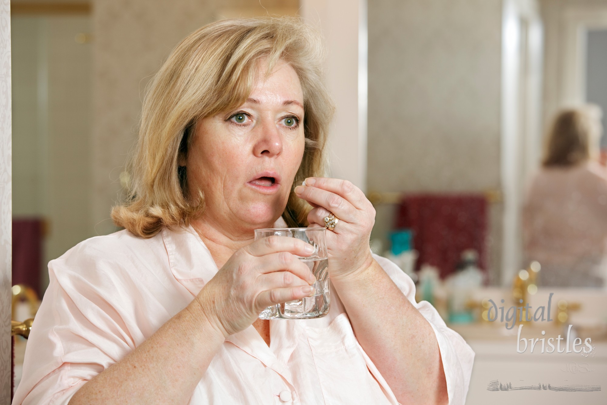 Mature woman's morning routine - taking medicine with glass of  water