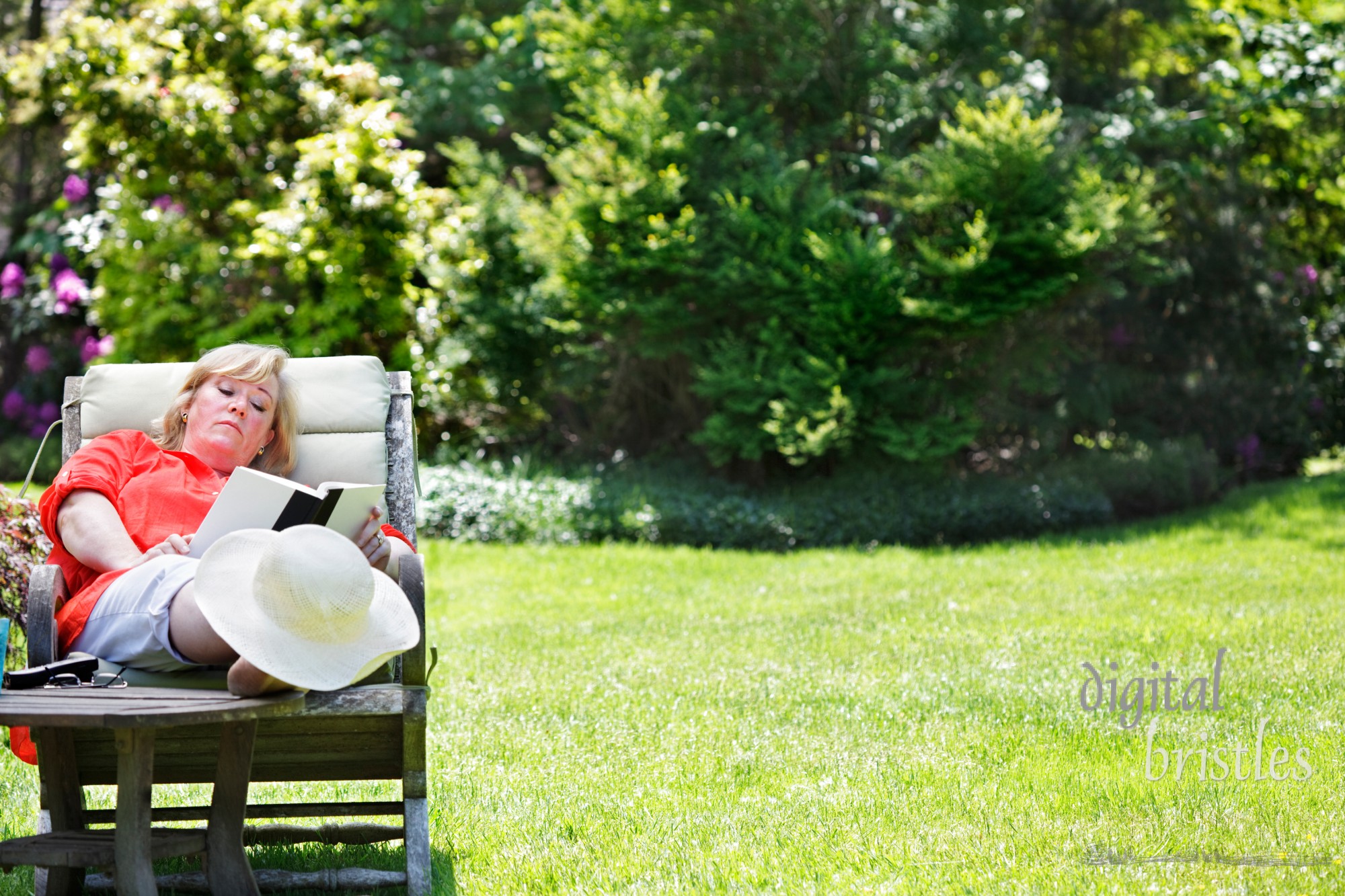 Mature woman reading in a sunny garden chair