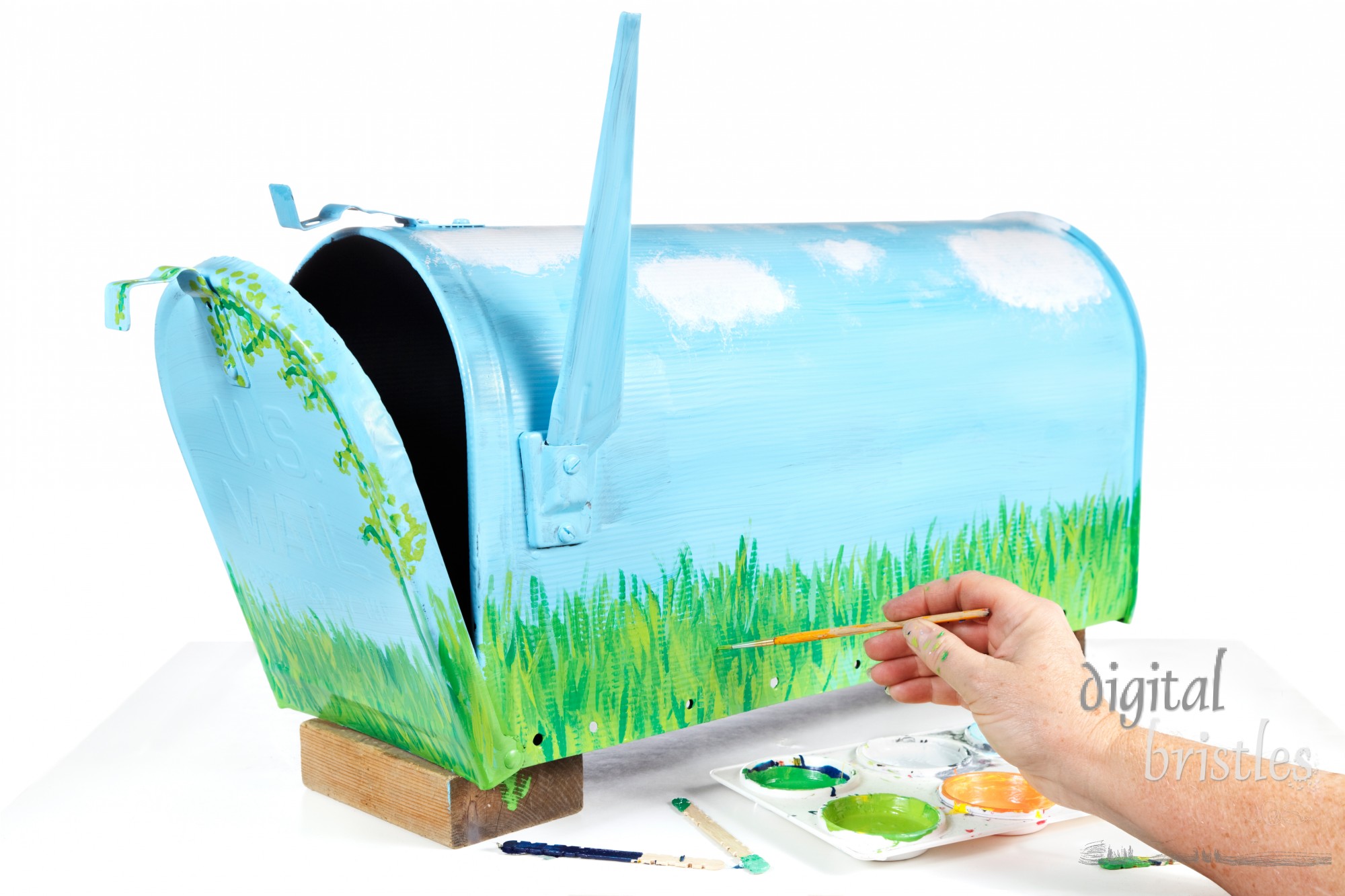 Woman's hand with paint tray & brush working on hand painting a mailbox