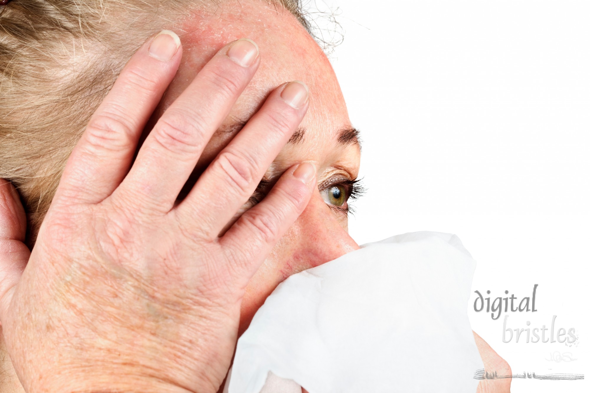 Mature woman blows her nose and holds her head