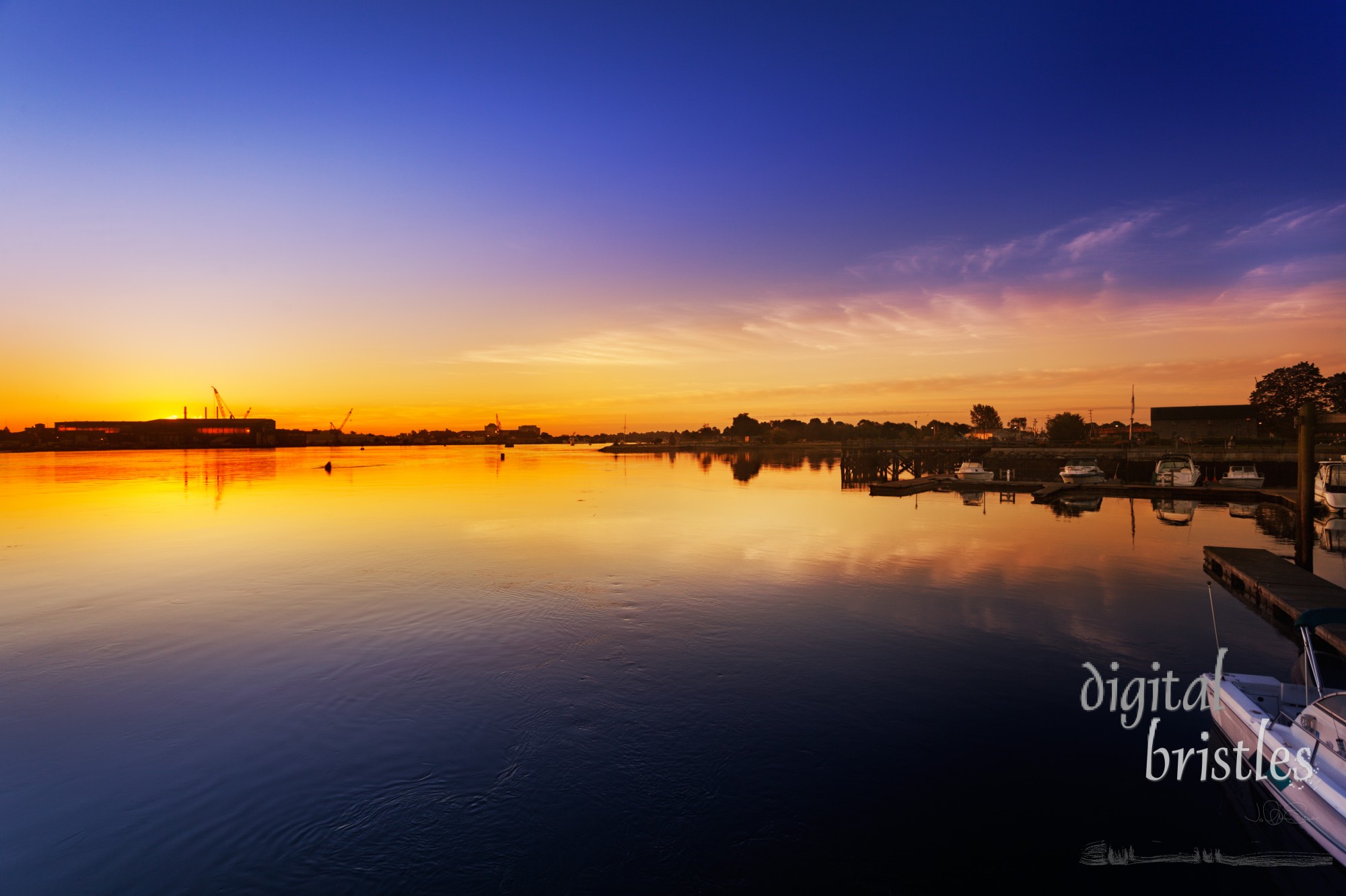 Piscataqua River, Portsmouth, New Hampshire with the sun rising behind the Navy Yard buildings in Kittery, Maine. Taken from Prescott Park