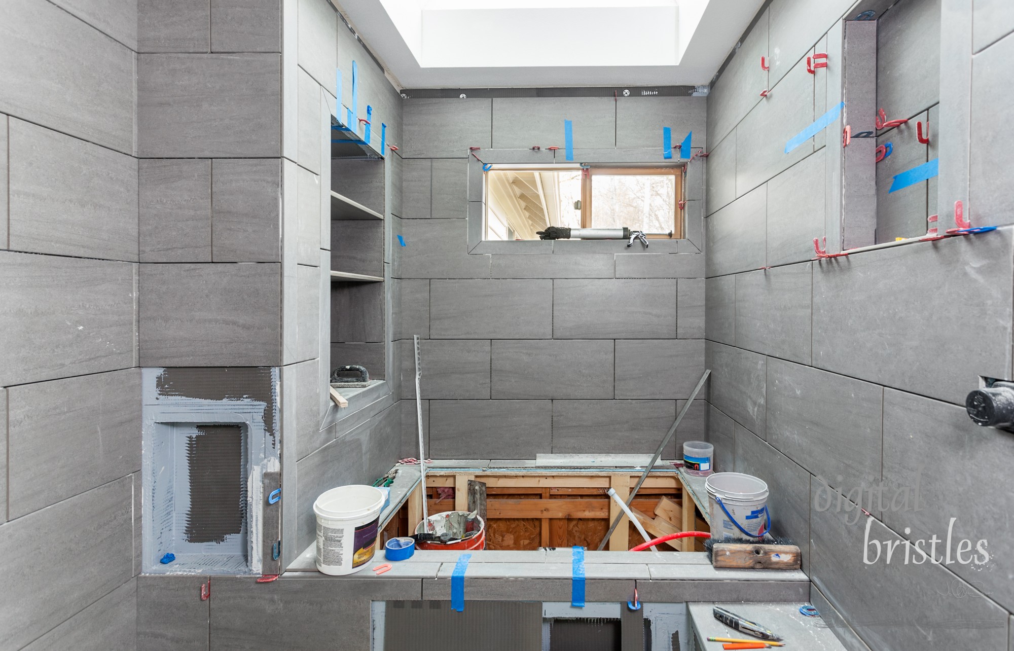 Wet room tiling in progress, including shelves, soap niche, toilet paper niche and shower seat