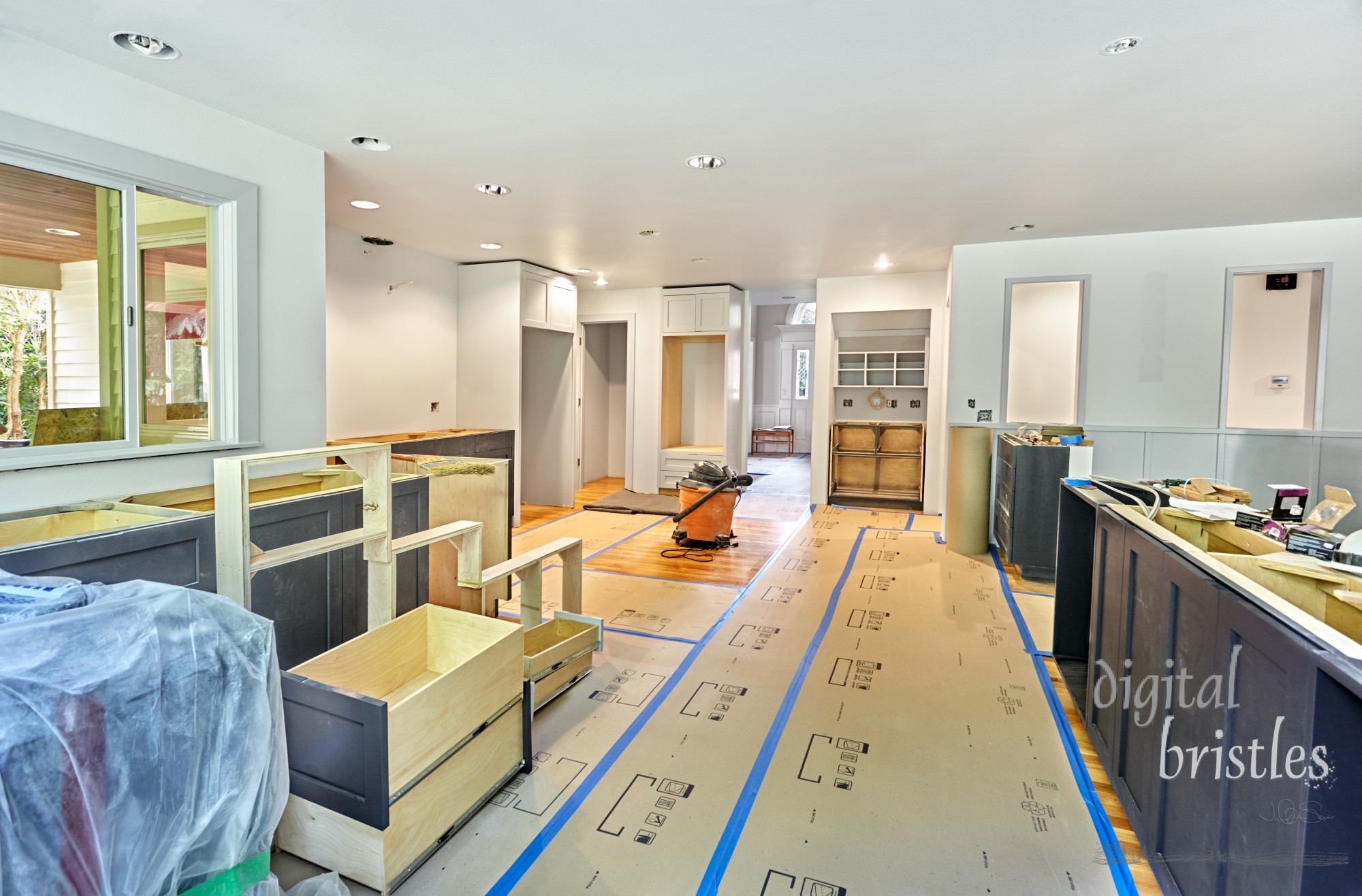 Kitchen cabinets in the process of being installed with frames and drawers stacked on the floor