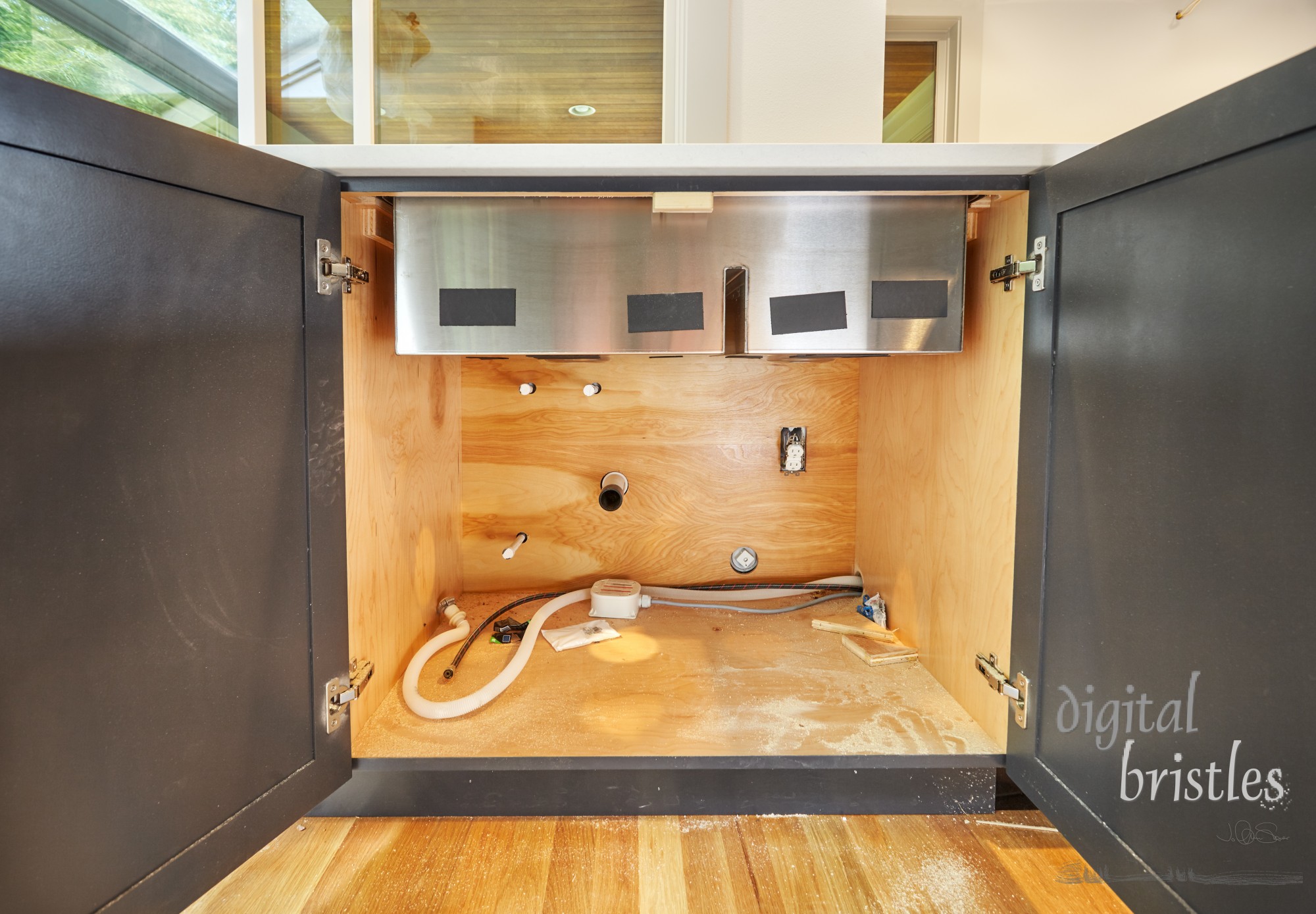 Stainless steel kitchen sink fitted in custom cabinet. . Pipes, drain and dishwasher connection incomplete