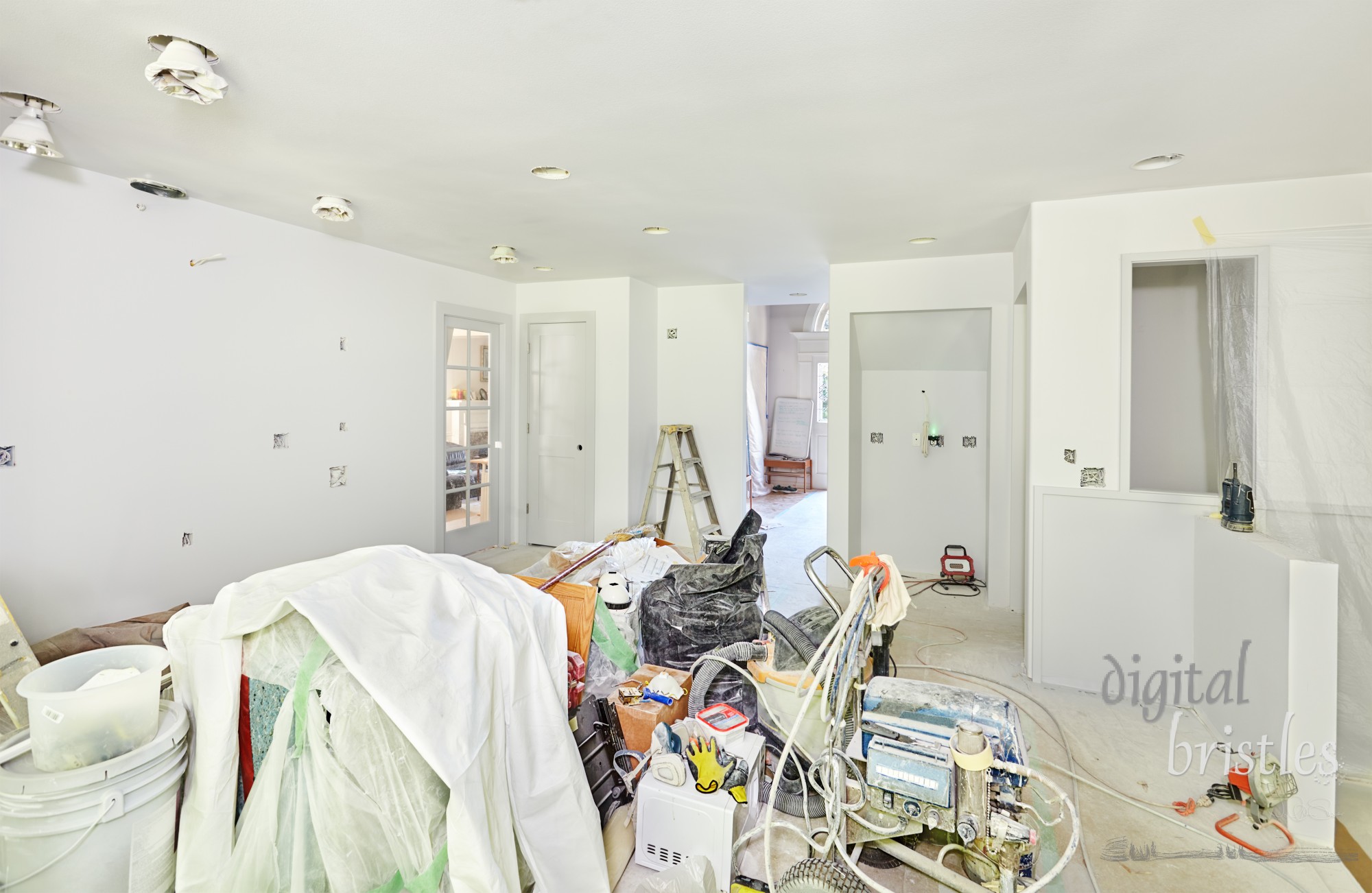 Rmodeling mess during priming and painting. Tools, supplies, trash and some wrapped appliances are shoved in the center of the kitchen