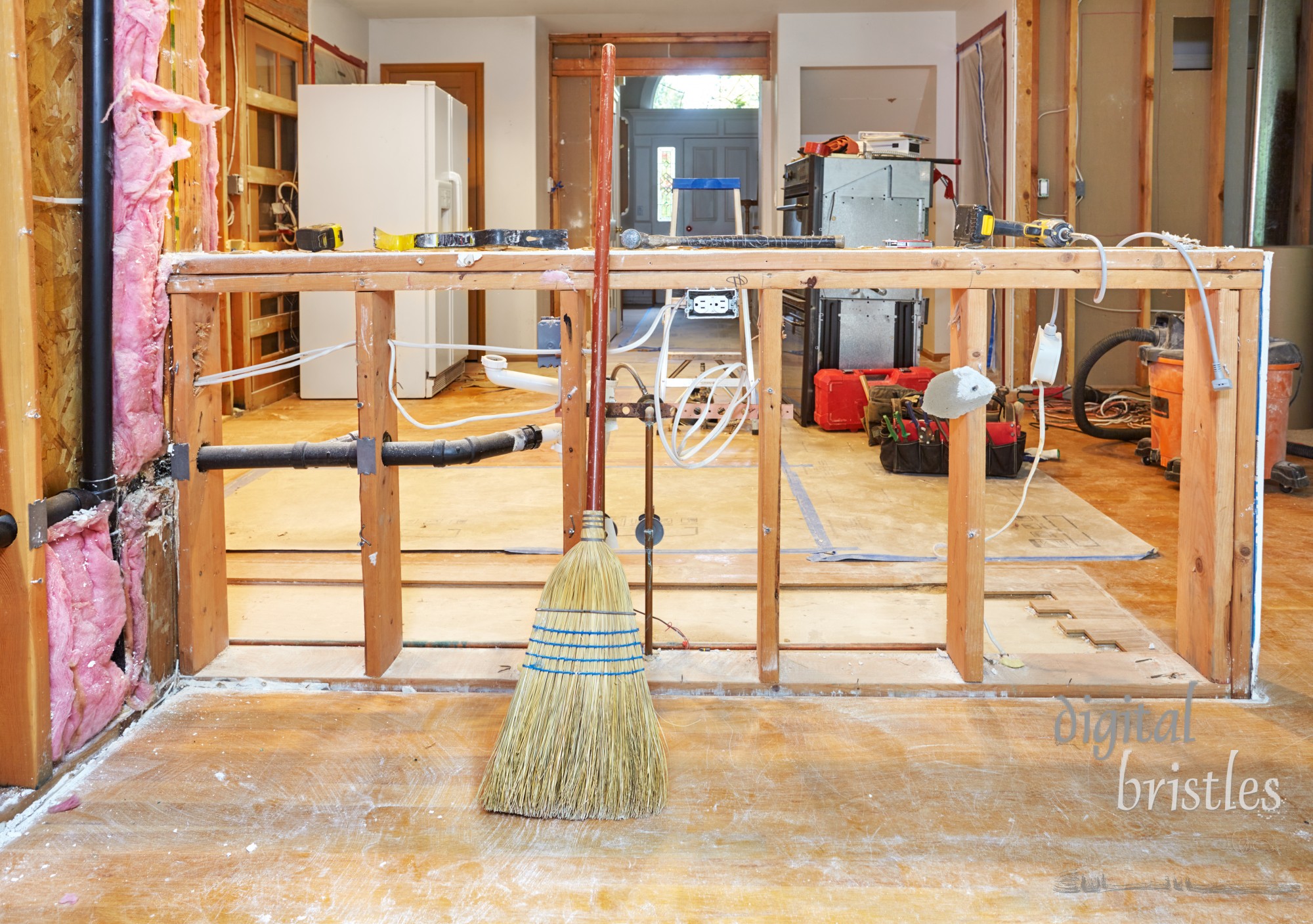 Old kitchen counter surfaces removed, with plumbing and electrical remaining in framing