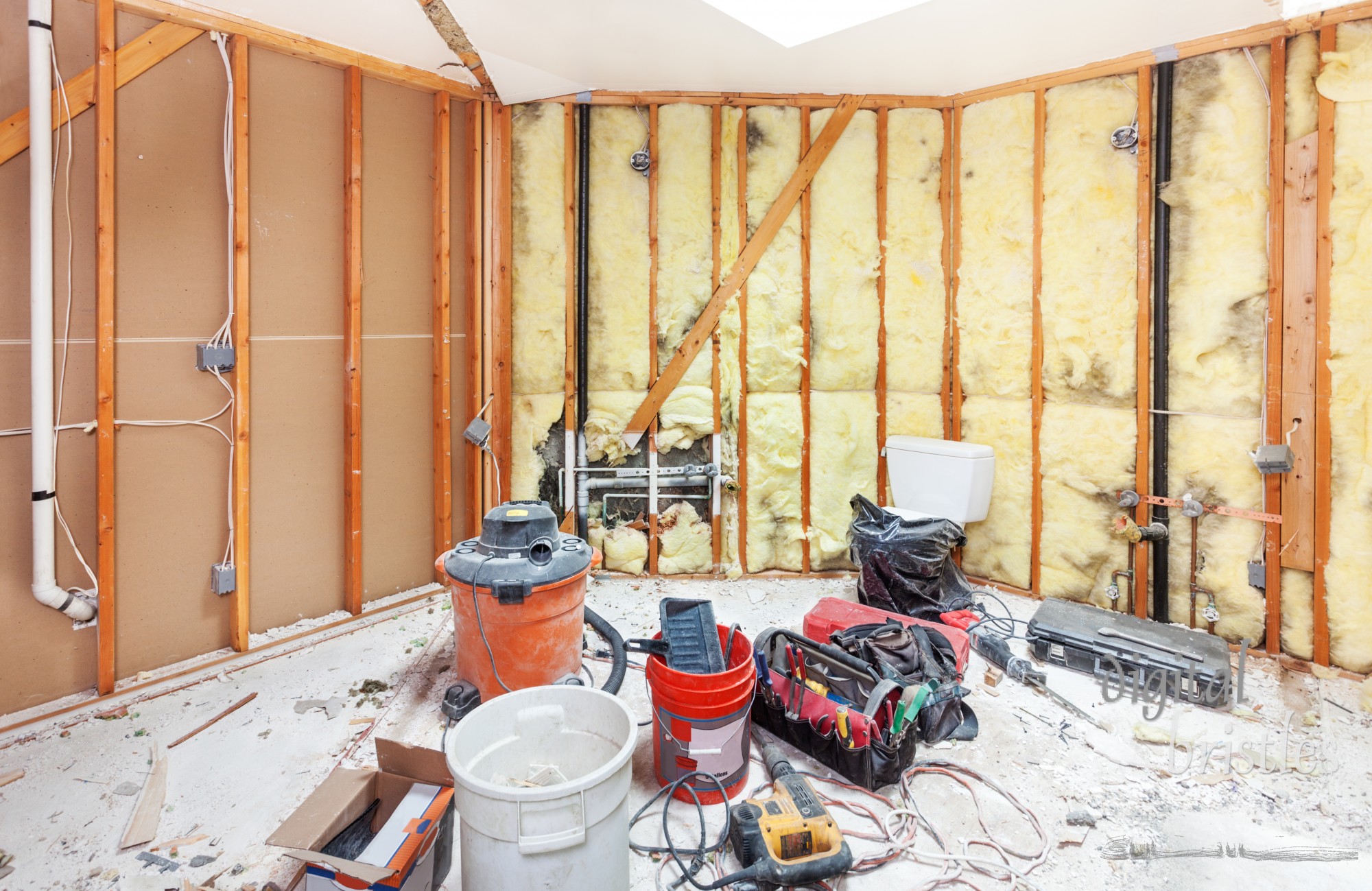 Tools for demolishing and cleaning up the debris from a master bathroom to be remodeled. Walls torn back to studs