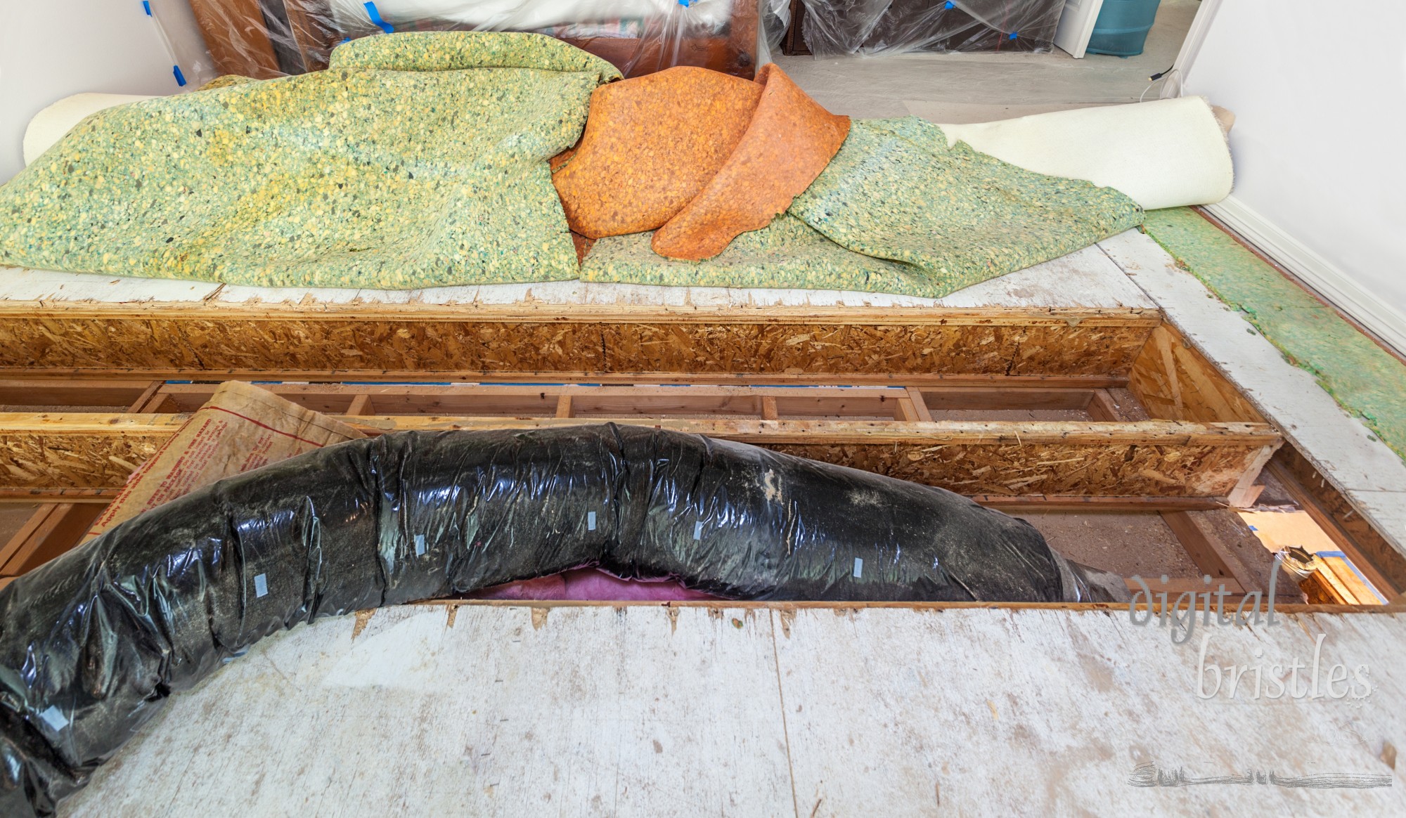 Floor joists exposed and insulated heating duct removed as part of a remodeling project