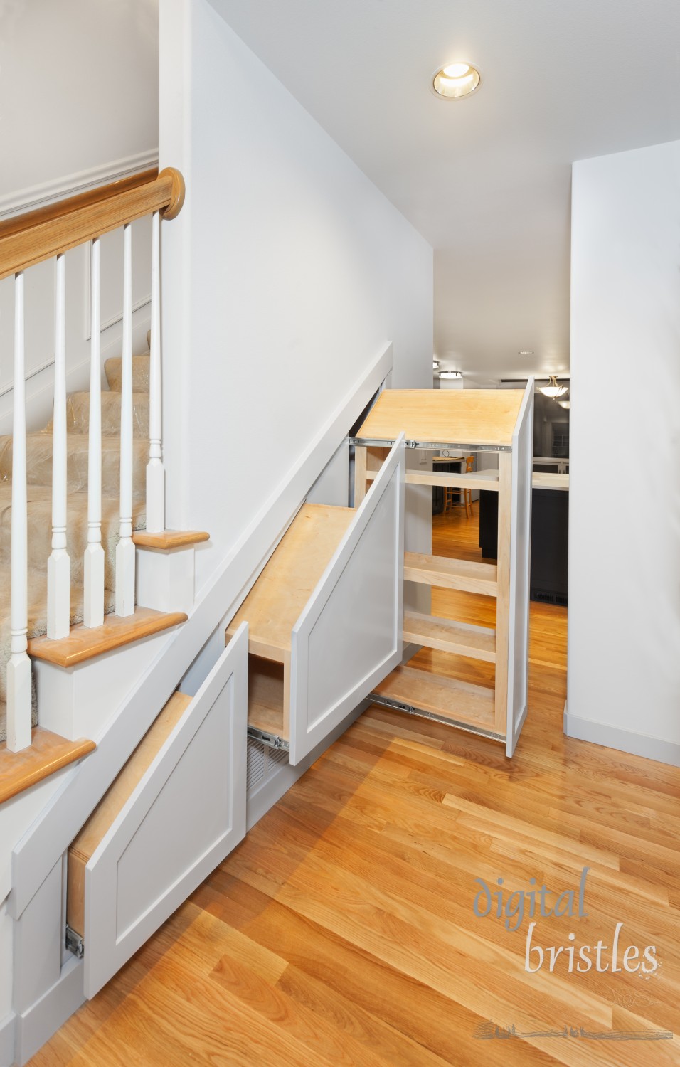 Under-stair pullout cabinets installed in openings with decorative fronts attached (but no handles)