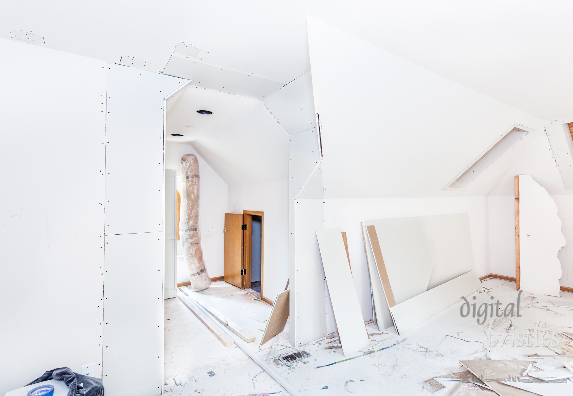 Careful drywall hanging around angled ceiling and wall segments during a home remodel