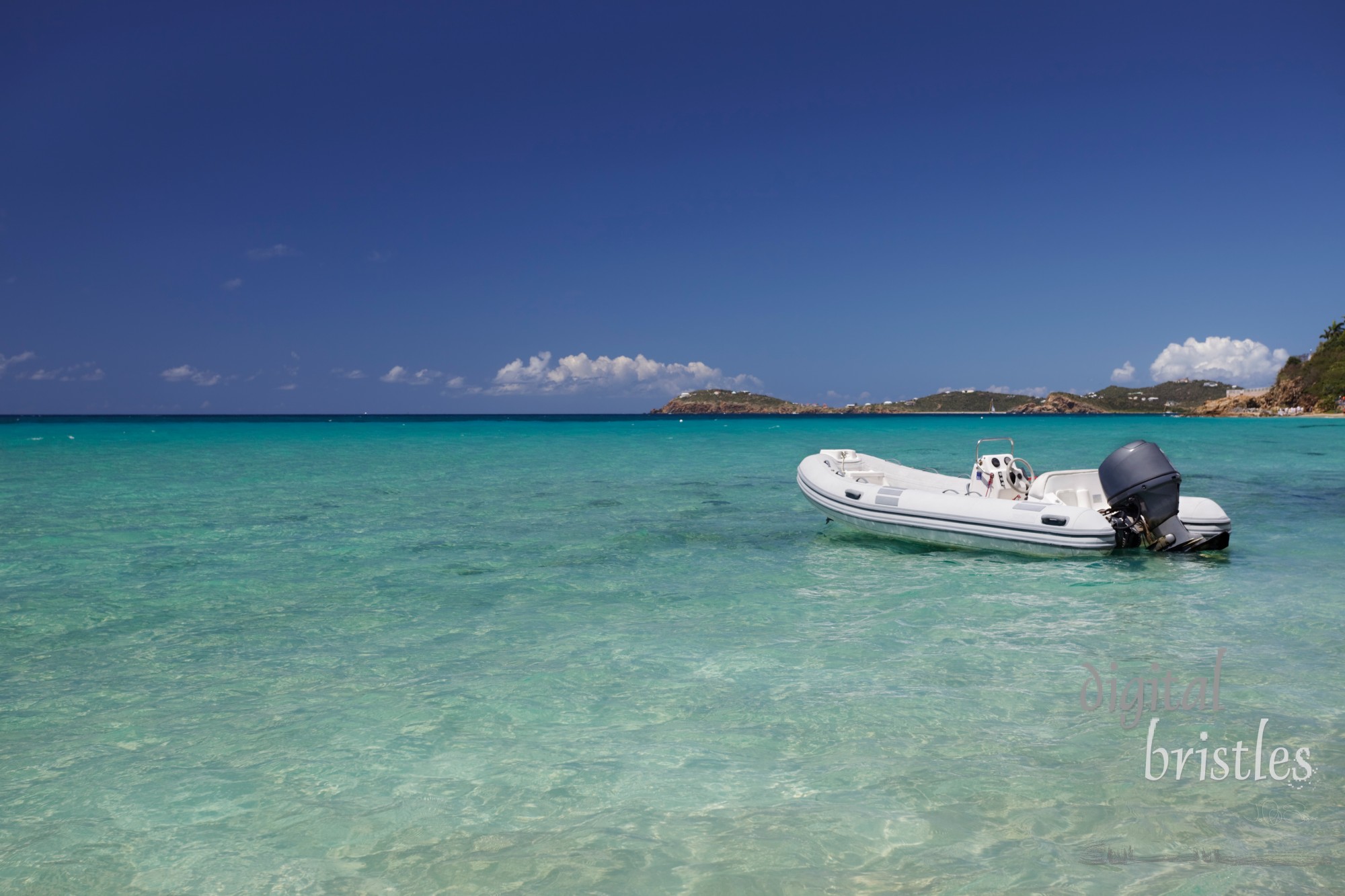 Dinghy with outboard motor anchored in a tropical bay