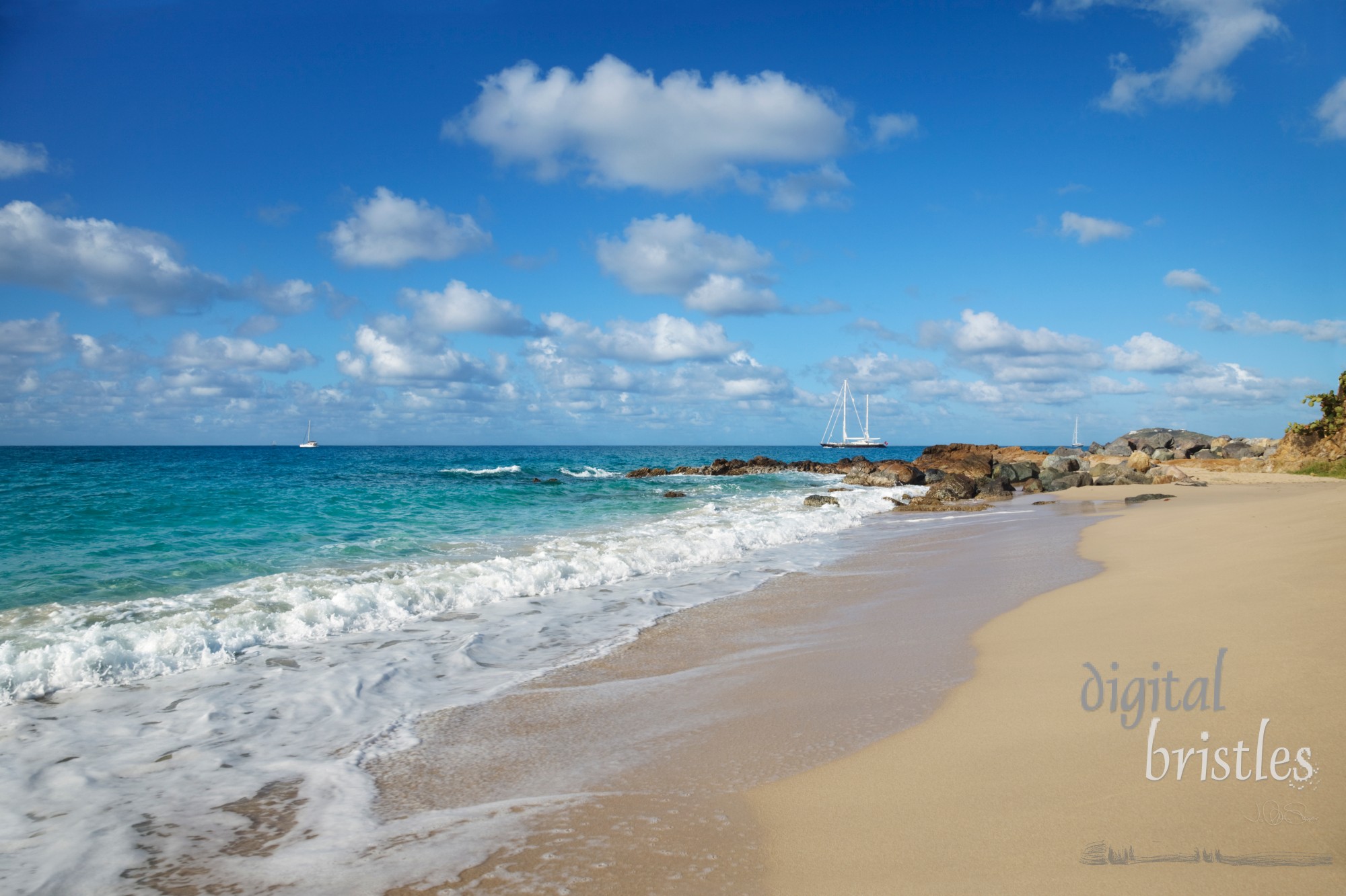 Tropical beach with sailboats in the distance