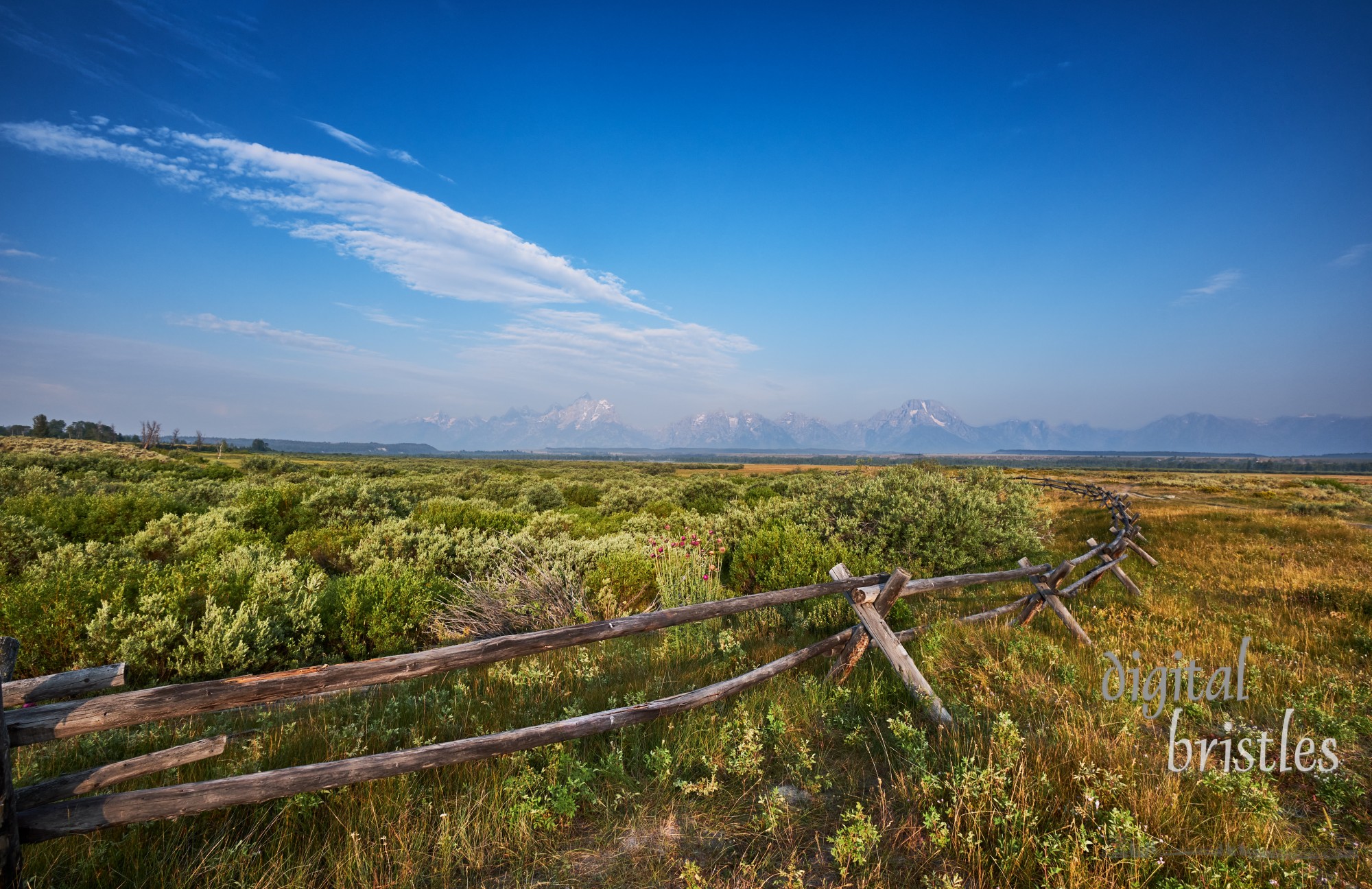 Old fashioned split rail wooden fence on the land of Cunningham Ranch, Moose, Wyoming. Teton mountains in the distance to the West