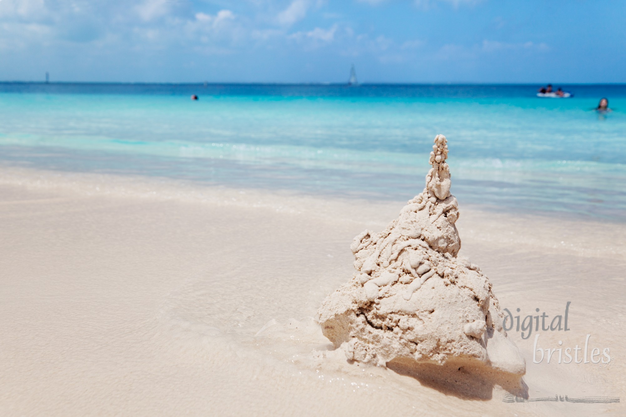 Young girl watches from the water as waves begin to erode her sandcastle, Grace Bay beach, Turks & Caicos