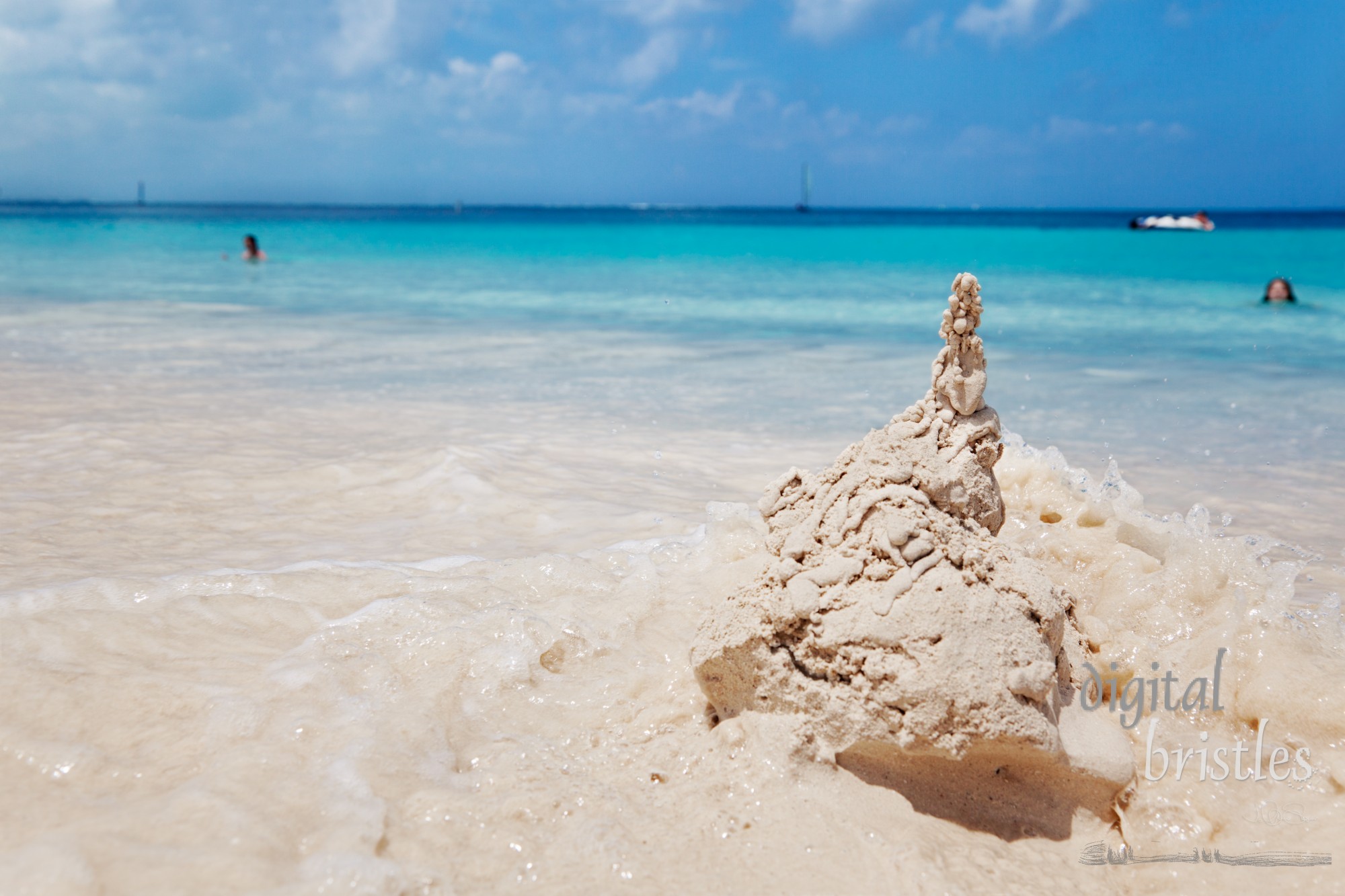 Young girl watches from the water as a wave smacks into her sandcastle, Grace Bay beach, Turks & Caicos