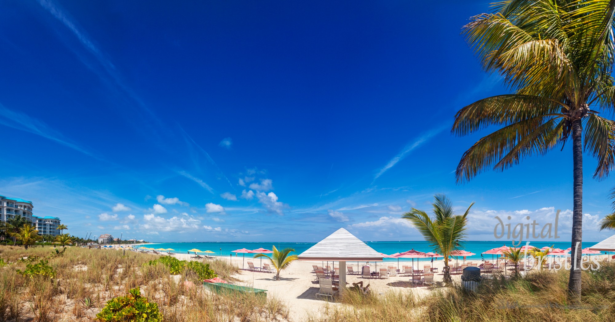 A long sweep of the white sands and turquoise waters of Grace Bay beach on a sunny spring morning