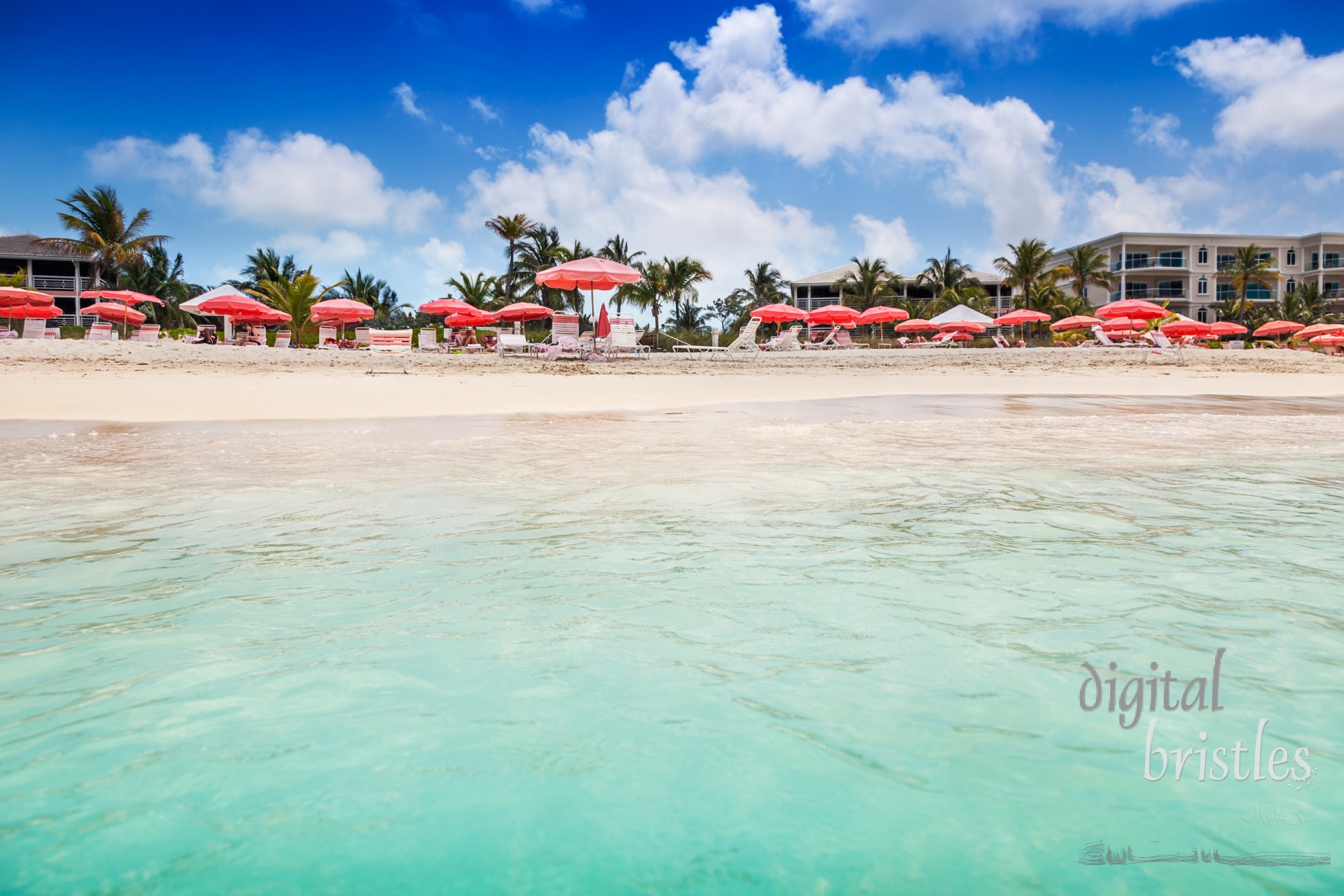 Clear calm waters lap the white sands of an umbrella studded Grace Bay Beach, Turks and Caicos