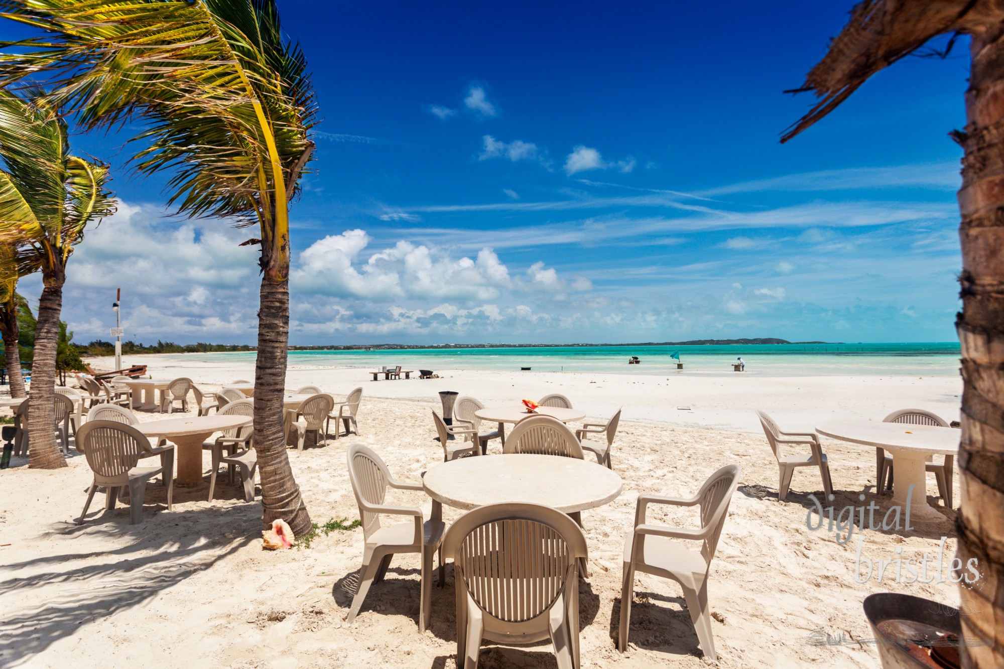 White sand, palm trees and a turquoise bay by tables on the beach, Providenciales, Turks and Caicos